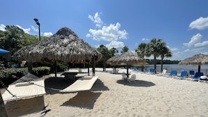 Une plage avec des parasols en chaume, des chaises longues et des hamacs.