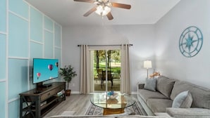 A living room with a television, sofa, coffee table, and ceiling fan. - Spacious 1st floor in Bahama Bay, Resort Amenities. Disney, less than 15 mins (Davenport)