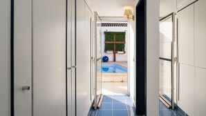 Un pasillo que lleva a una piscina con vistas a un jardín y una pérgola.