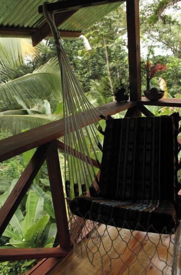 Relax in a serene garden setting, where a hammock and small table invite you to unwind amidst lush greenery.