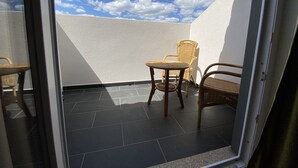 A balcony with a white wall, a tiled floor, and two wicker chairs. - Casa Do Vidoeiro (Seia)