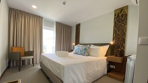 A hotel room with a large bed, a chair, a nightstand, and a decorative wall panel. - Casa Do Vidoeiro (Seia)
