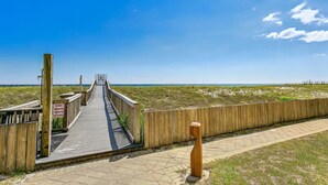 A wooden boardwalk leading to a beach, with a sign warning about wet sand. - Salt and Sunlight: Spacious, airy 9th Floor Navarre Towers condo located on the Gulf! (Navarre)