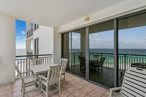 Un balcone con tavolo e sedie, vista sull'oceano e un edificio sullo sfondo.