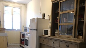 A kitchen with a refrigerator, microwave, oven, and wooden cabinets. - Cosy, renovated family home in the heart of the Pyrenees (Eaux-Bonnes)