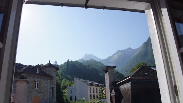 A view from a window overlooking a valley with buildings and mountains. - Cosy, renovated family home in the heart of the Pyrenees (Eaux-Bonnes)