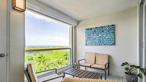 Un balcón con vistas a un paisaje verde, un sofá, una mesa y una planta en maceta.