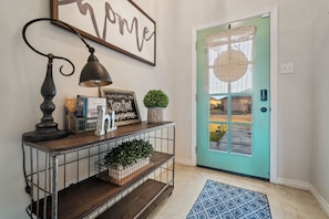 Enter a charming entryway with a welcoming sign, vintage lamp, and console table.