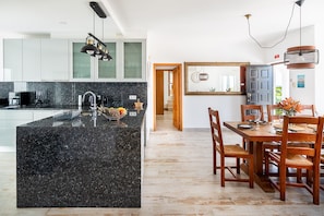 Eine moderne Küche mit einer Granitinsel, Edelstahlgeräten und einem Essbereich mit Holztisch und Stühlen.