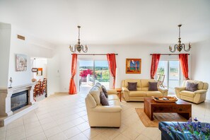 A spacious living room with a fireplace, two sofas, a coffee table, and a view through large windows.