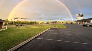 A parking lot with a rainbow, a building with a billboard, and a grassy area. - Relax Inn Smyrna Dover Coastal Gateway (Smyrna)
