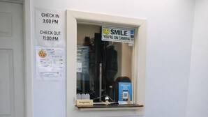 A room with a window displaying a menu, a sign indicating check-in and check-out times, and a chair. - Relax Inn Smyrna Dover Coastal Gateway (Smyrna)