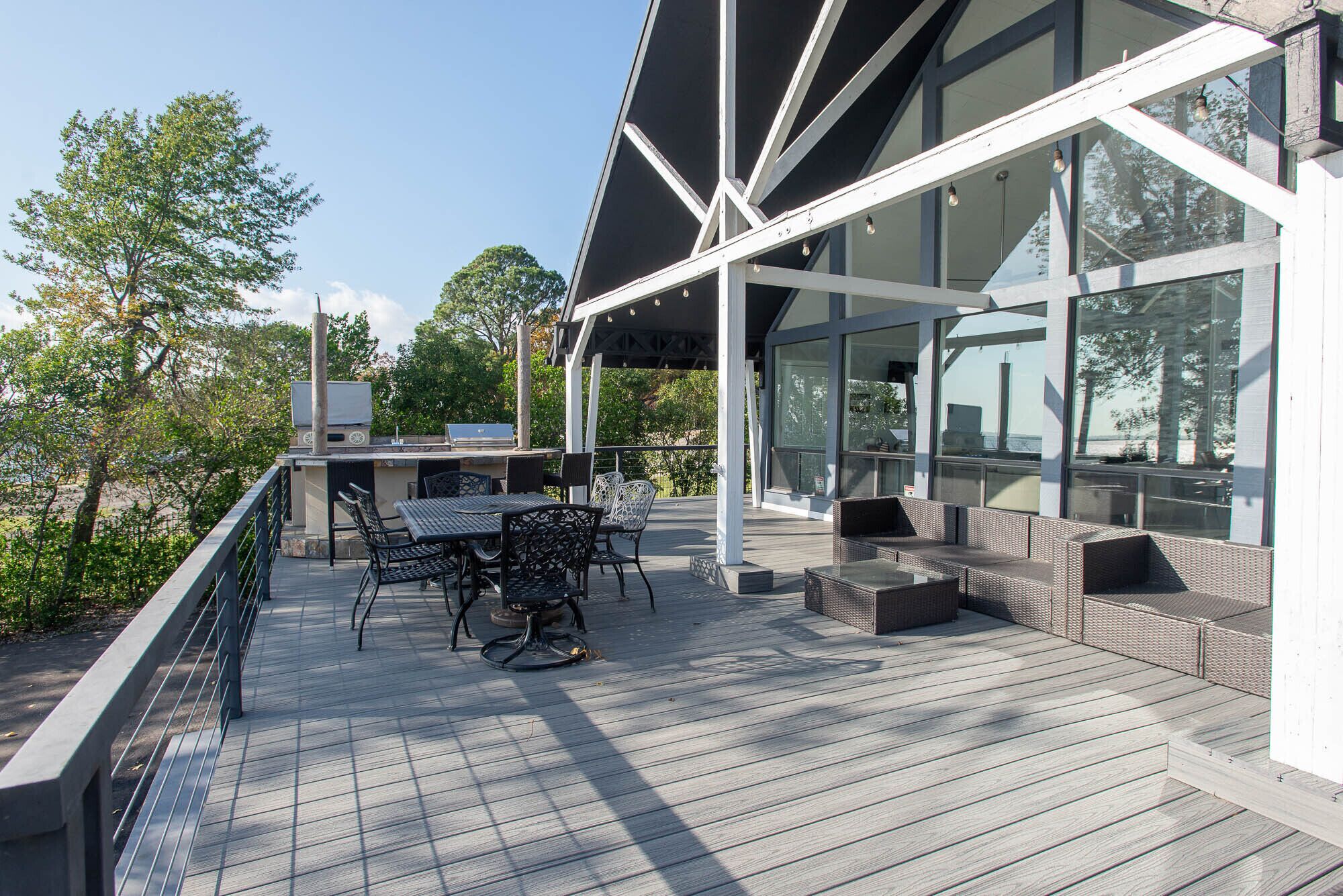 Een modern terras buiten met een eethoek, grote ramen en uitzicht op het omliggende landschap.