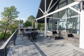 Une terrasse extérieure moderne dotée d’un espace repas, de grandes fenêtres et offrant une vue sur le paysage environnant.