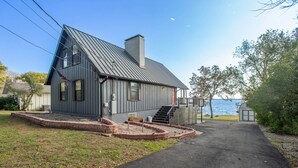 Ett tvåvåningshus med ett tak av metall, en veranda och utsikt över vattnet.