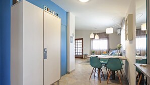 Eine moderne Küche mit Essbereich, mit einem großen Schrank mit der Aufschrift 'BEACH', einem Esstisch mit Stühlen und einem fenster mit Vorhängen.