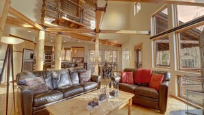 A spacious living room with a brown leather sofa, a wooden coffee table, and a staircase leading to an upper level.