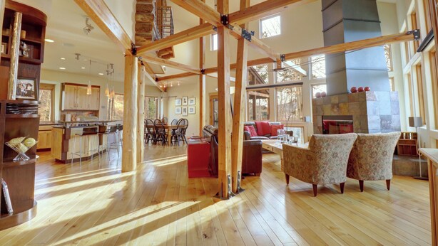 A spacious living area with wooden beams, a fireplace, and a view of the outdoors.