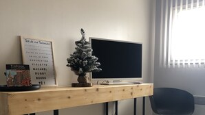 Une chambre avec un bureau en bois, une petite plante en pot, un menu encadré et une chaise noire.