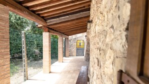 A covered corridor with stone walls, wooden beams, and a brick floor.
