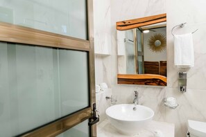 A modern bathroom with a glass shower enclosure, a white sink, and a wooden-framed mirror.
