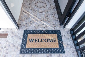 A welcome mat with the word "WELCOME" on a tiled floor.
