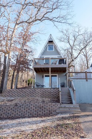 A two-story house with a balcony, a front door, and a staircase leading up to the entrance.