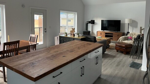 A spacious living area with a wooden dining table, a sofa, and a TV.