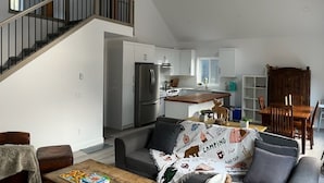 A modern living room with a sofa, coffee table, and a staircase leading to a kitchen.