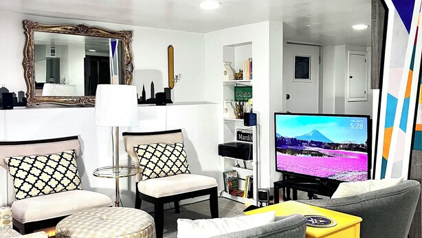 Un salon moderne comprenant un canapé, des fauteuils, une table basse et un téléviseur.