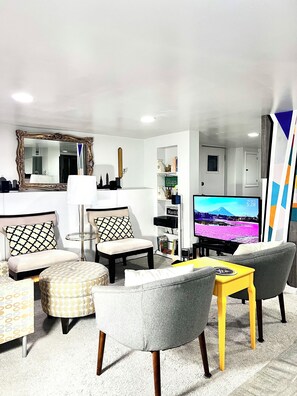 Ein modernes Wohnzimmer mit einer Couch, Sesseln, einem Couchtisch und einem Fernseher.