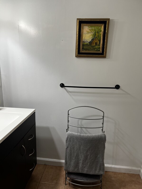 Ein Badezimmer mit einem weißen Waschbecken, einem Handtuchhalter und einem Bild an der Wand.