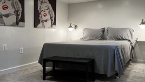 Une chambre à coucher comprenant un lit, des tables de chevet et deux lampes fixées au mur.