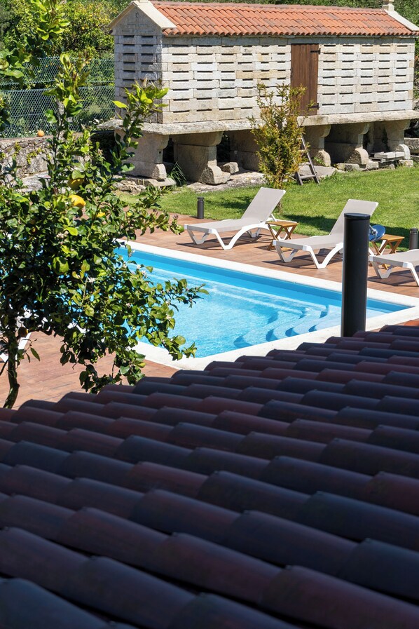 A swimming pool with lounge chairs, a stone building, and a tiled roof. - Casa Rural Laxido (Rianxo)