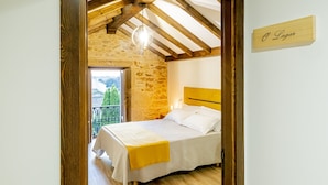 Een slaapkamer met een bed, een houten hoofdbord, een stenen muur, een balkon met een hekwerk en een bordje met de tekst 'O Lagar'.