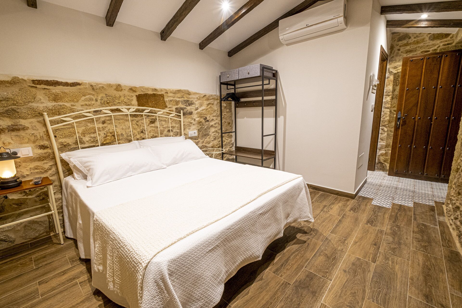 Un dormitorio con pared de piedra, una cama litera, suelo de madera y una puerta con fachada de piedra.