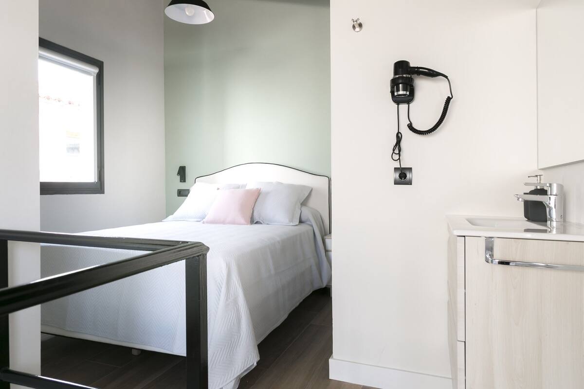 Une chambre moderne avec un lit, un bureau et un téléphone fixé au mur.