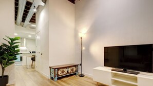 A modern living room with a flat-screen TV, a floor lamp, and a decorative cabinet. - Heredia Suites Centro (Málaga)
