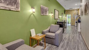 A hallway with green walls, a wooden table with a sign, two grey armchairs, and framed pictures on the walls. - 1892 suite at Ore House Inn (New Castle)