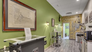 A reception area with a counter, framed map, and wall-mounted lights. - 1892 suite at Ore House Inn (New Castle)