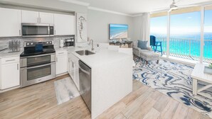 Una cocina moderna con electrodomésticos de acero inoxidable, un comedor con vistas al océano y un amplio ventanal.