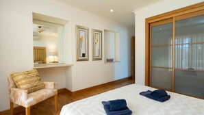 A hotel room with a bed, a chair, a mirror, and artwork on the wall. - Wide 3 bedrooms apartment wifi, air conditioning, garage (Alto do Semino, Quarteira)