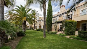A well-maintained courtyard with palm trees, neatly trimmed hedges, and a clear sky. - Wide 3 bedrooms apartment wifi, air conditioning, garage (Alto do Semino, Quarteira)