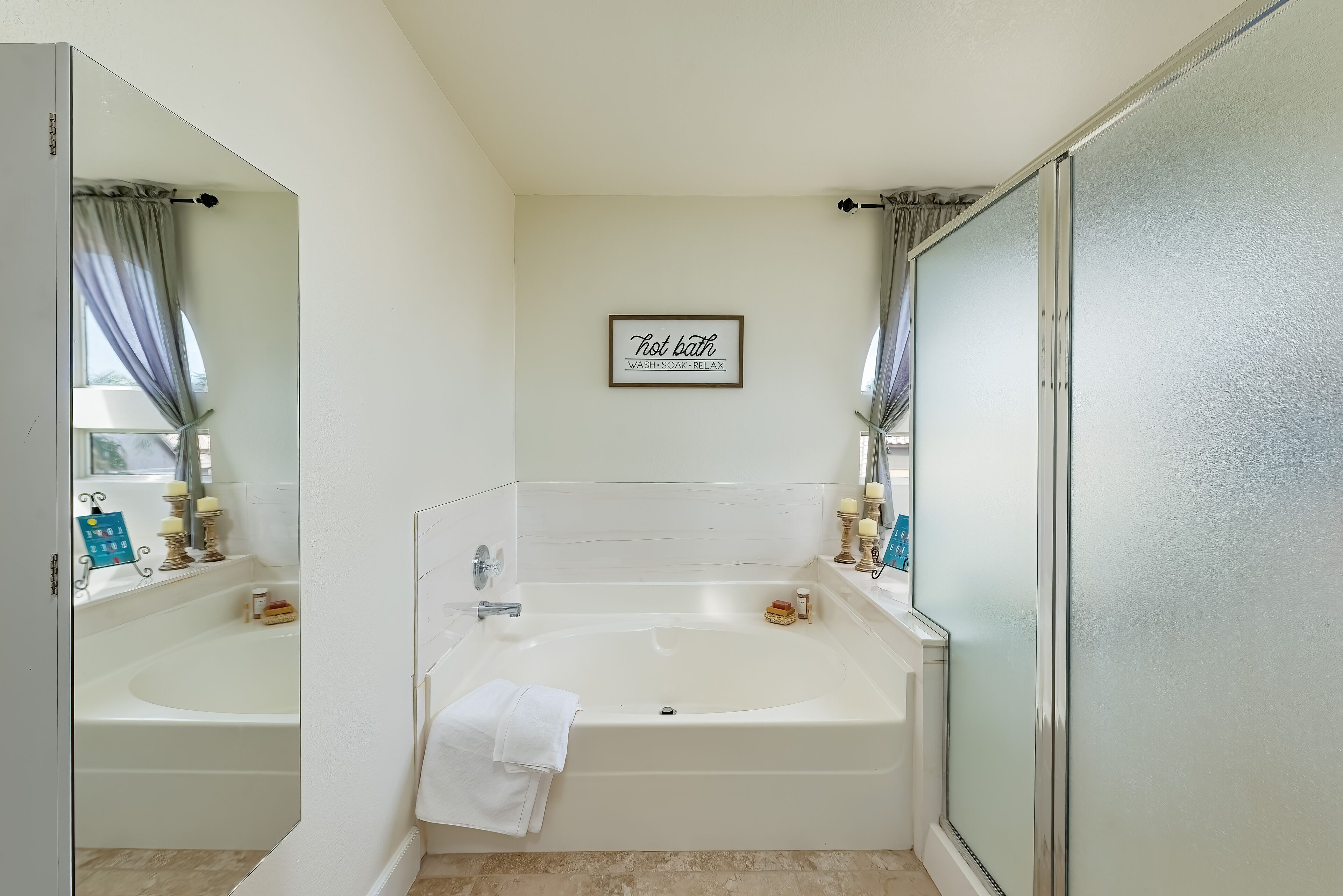 A modern bathroom with a bathtub, a shower, and a large mirror.