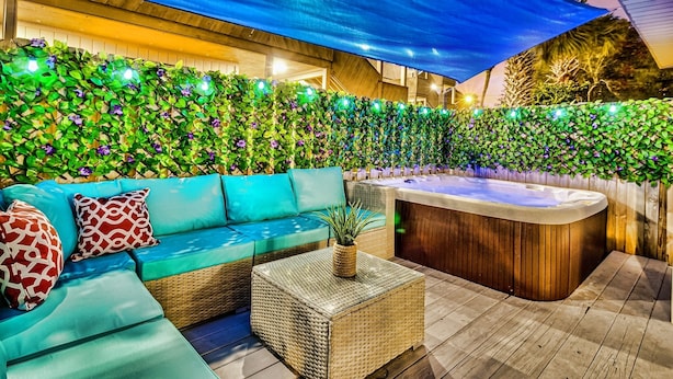 Un espace patio aménagé avec un canapé bleu, une table basse en osier et un jacuzzi.