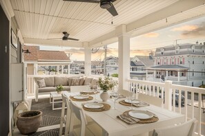 A covered balcony with a dining table set for four, a sofa, and a potted plant. - Luxury Beach Condo  - downtown area in Ocean City, NJ (Ocean City)