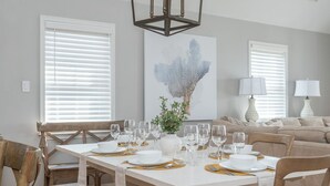 A dining area with a wooden table set for six, surrounded by wooden chairs.