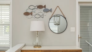 A bathroom with a wooden vanity, a round mirror, and a wall-mounted fish decoration.