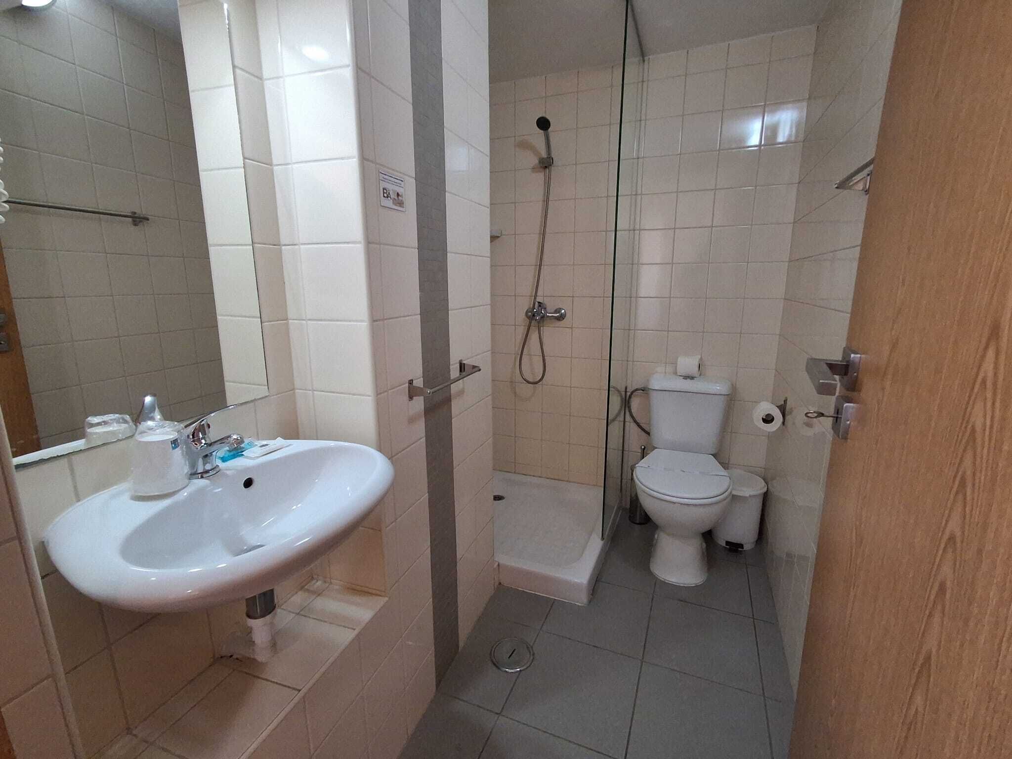 A small bathroom with a sink, toilet, and shower.