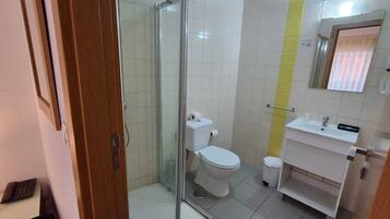 Un baño con cabina de ducha de vidrio, inodoro, lavabo y espejo.
